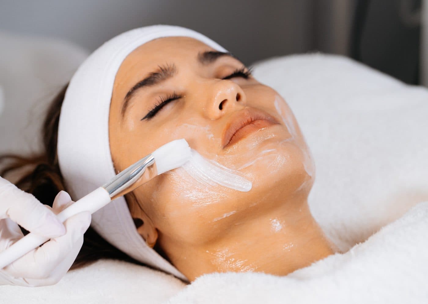 Client resting with a treatment mask while an esthetician works